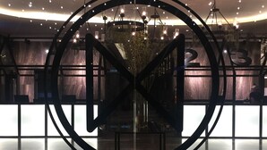 Eine moderne Lobby mit einer kreisförmigen Metallkonstruktion, einem Empfangstresen und einer Kronleuchter.
