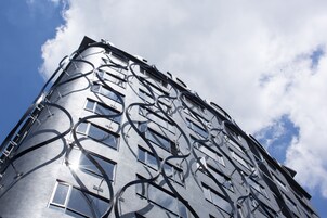 Un edificio moderno con un diseño arquitectónico único, con elementos metálicos curvados y numerosas ventanas.