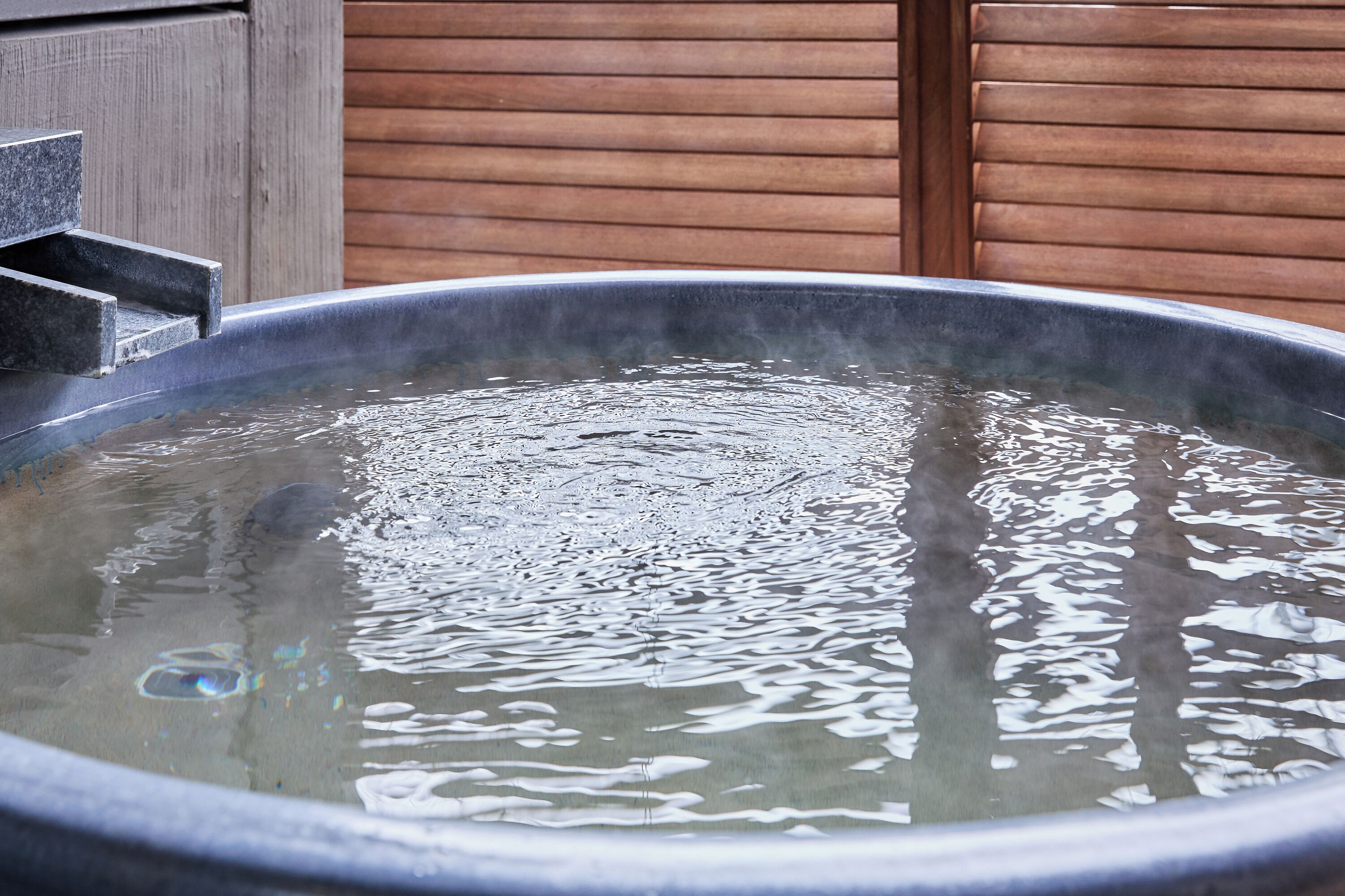 A hot tub with a wooden backdrop.
