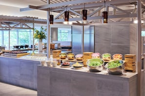 A buffet area with various food bowls, a white pergola, and hanging pendant lights.