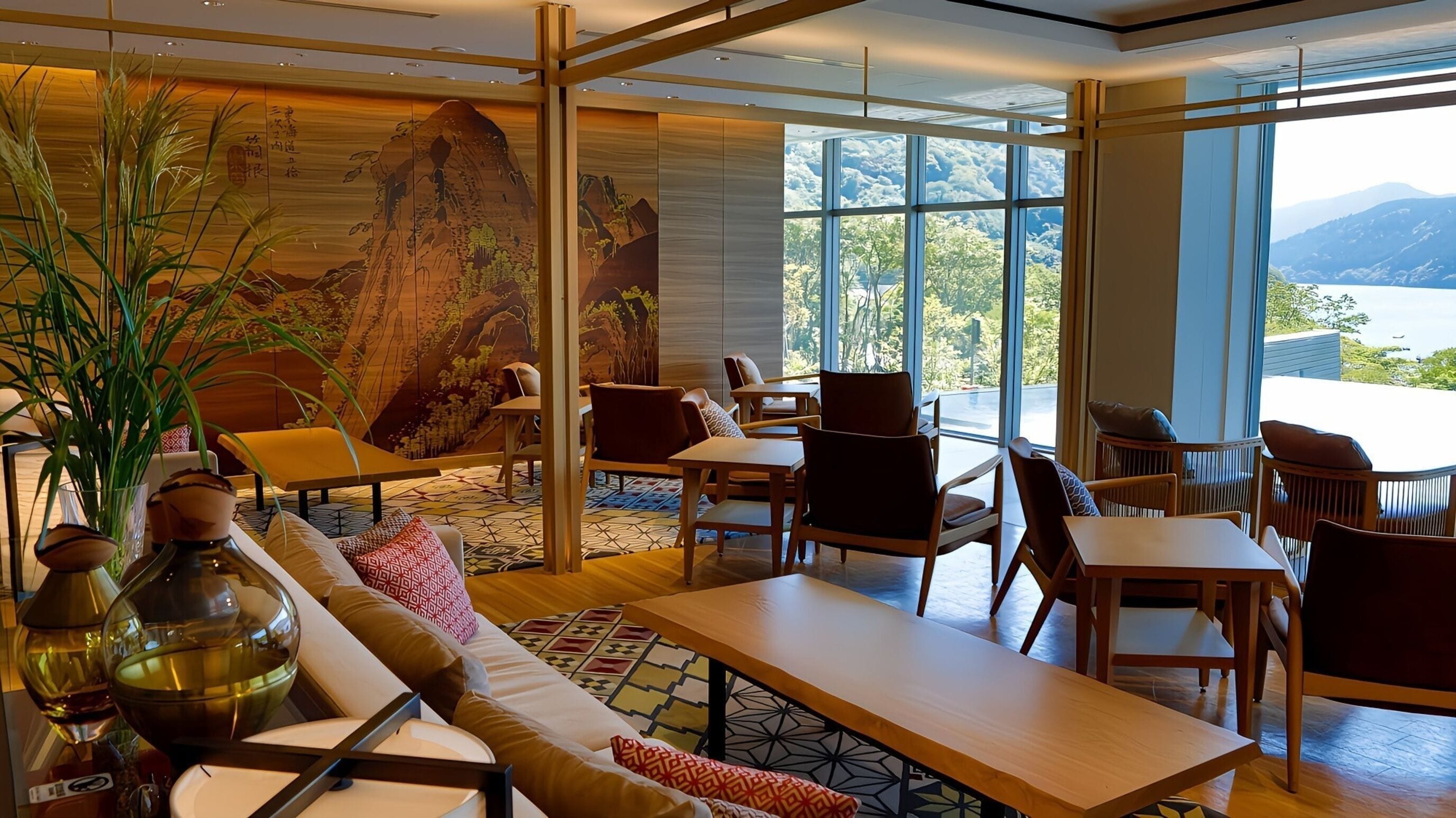 A modern hotel lobby with a large mural, comfortable seating, and large windows offering a mountain view.