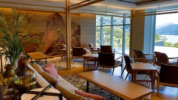 A modern hotel lobby with a large mural, comfortable seating, and large windows offering a mountain view.