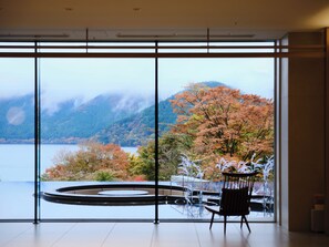 A room with a large window offering a view of a lake and autumn foliage. - Hakone Ashinoko Hanaori（ORIX HOTELS & RESORTS） (Hakone)