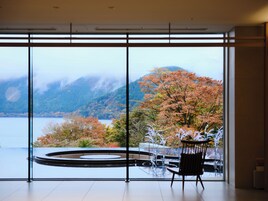Una habitación con un ventanal que ofrece vistas a un lago y follaje otoñal.