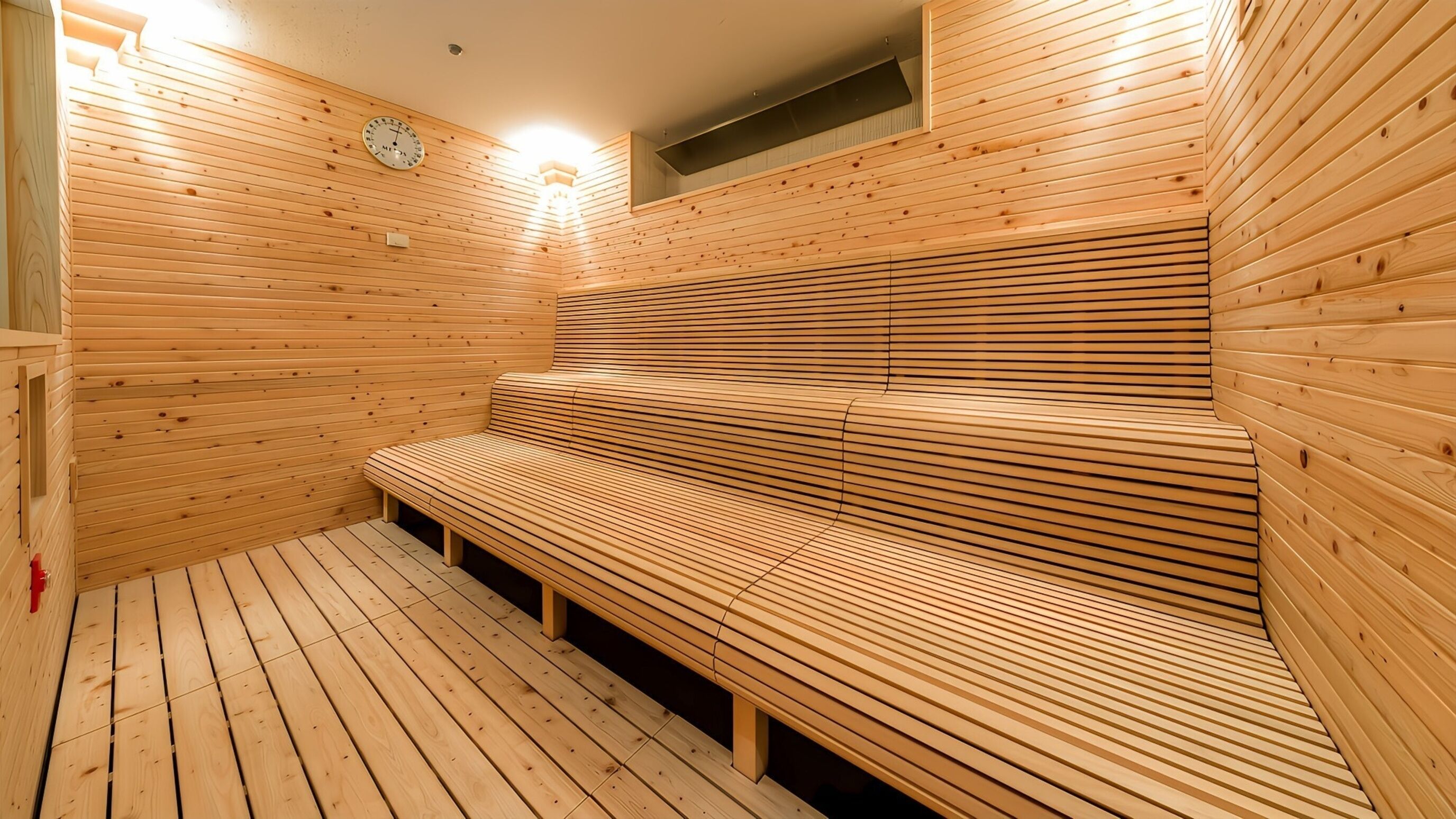 Una sauna con bancos de madera, un reloj en la pared y un ventanal pequeño.