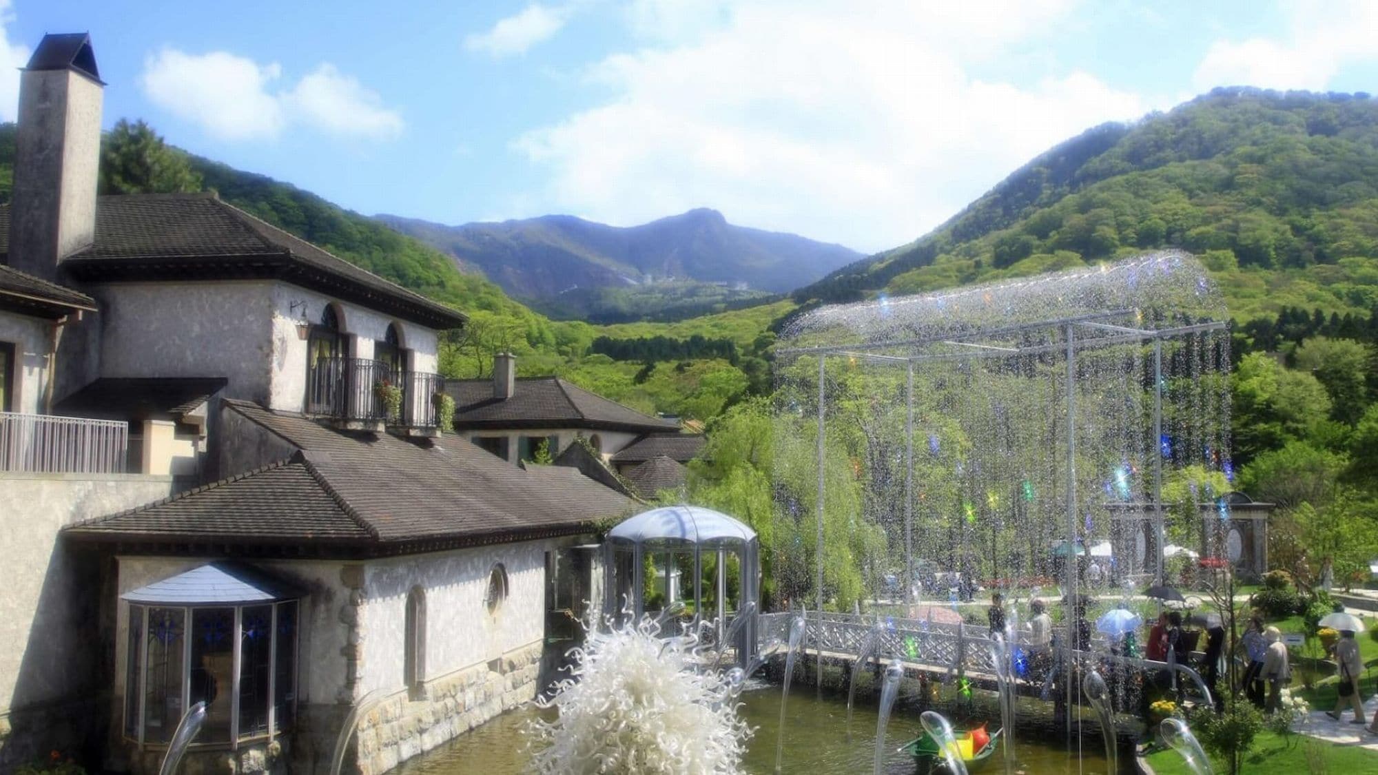 Un bâtiment traditionnel doté d’un jardin, d’une fontaine et d’un pont enjambant une rivière.