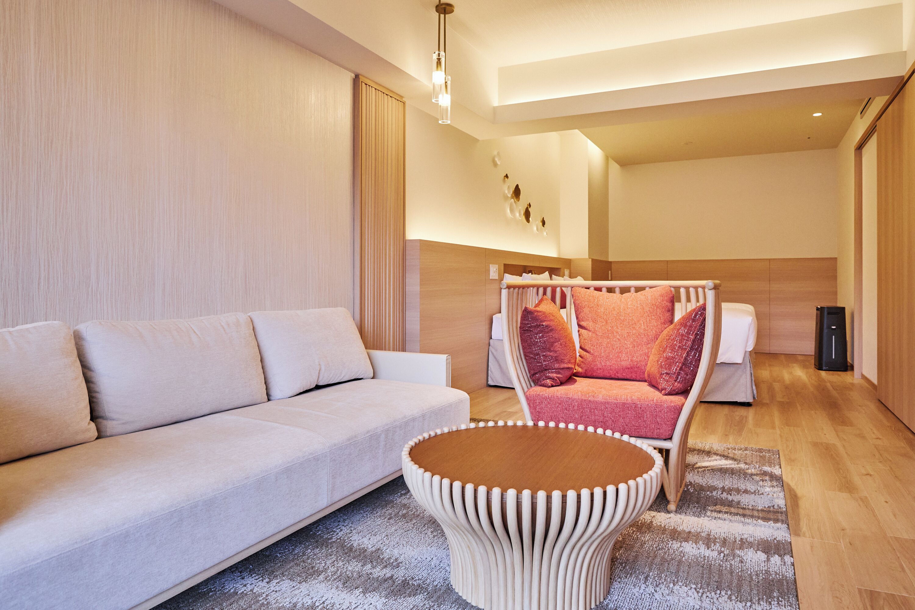 A modern hotel room with a sofa, a unique coffee table, and a bed with a canopy.