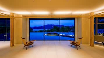 A modern room with a large window, two chairs, and a circular light fixture.