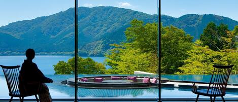 A room with a large window overlooking a pool and mountains.