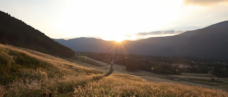 Paesaggio rurale con dolci colline, un sentiero ben definito e un villaggio in lontananza.
