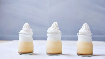 Tres vasos de postre con rellenos en capas y crema batida por encima.