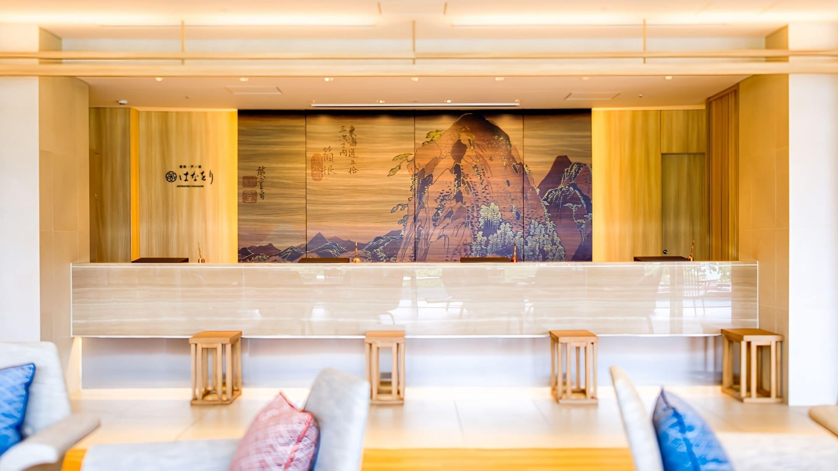 A reception area with a long counter, cushioned seating, and a large wall mural.