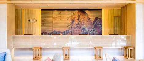 A reception area with a long counter, cushioned seating, and a large wall mural.