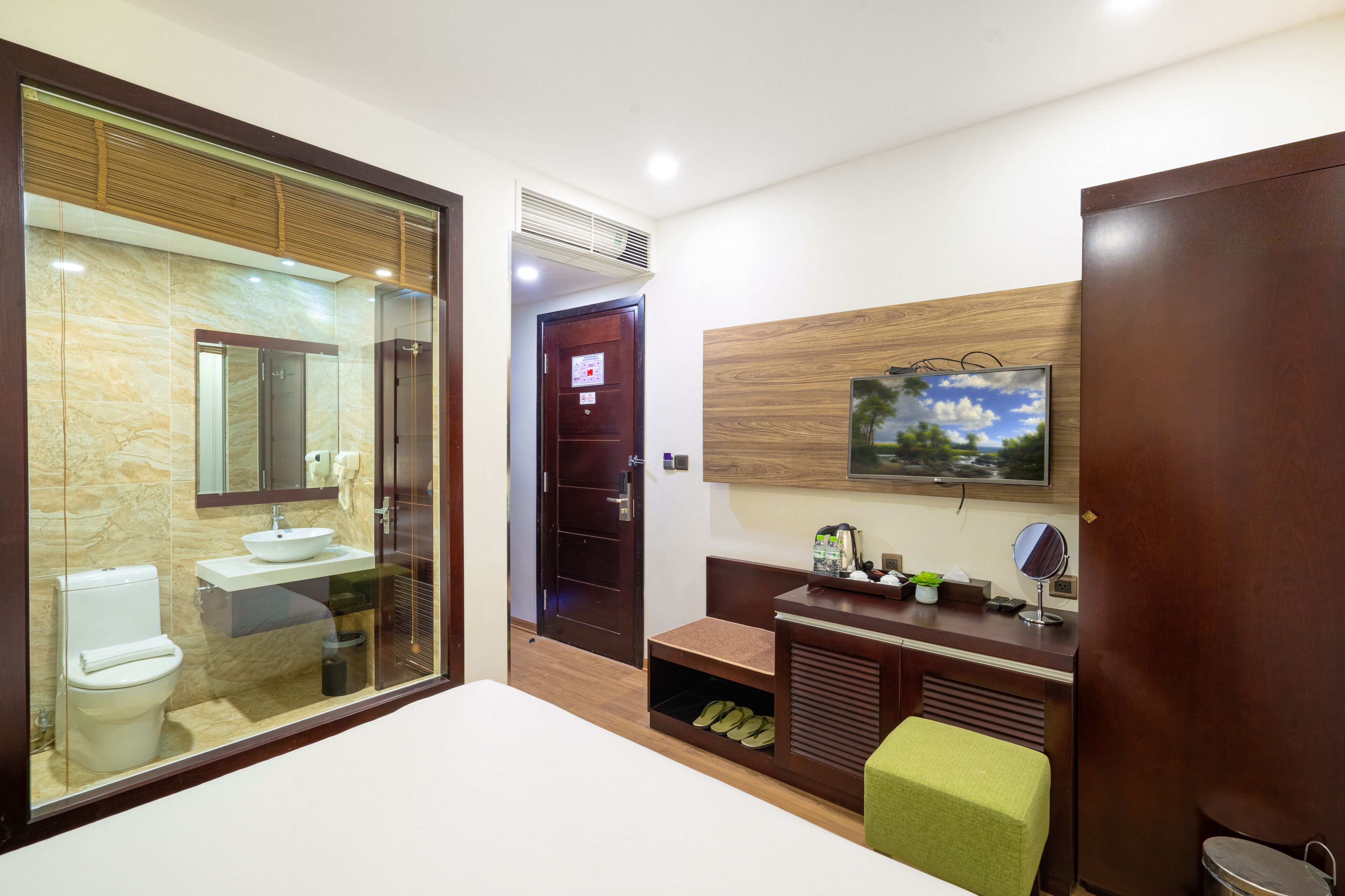 A modern bathroom with a glass enclosure, a sink, toilet, and a vanity with a mirror and small items on the counter.
