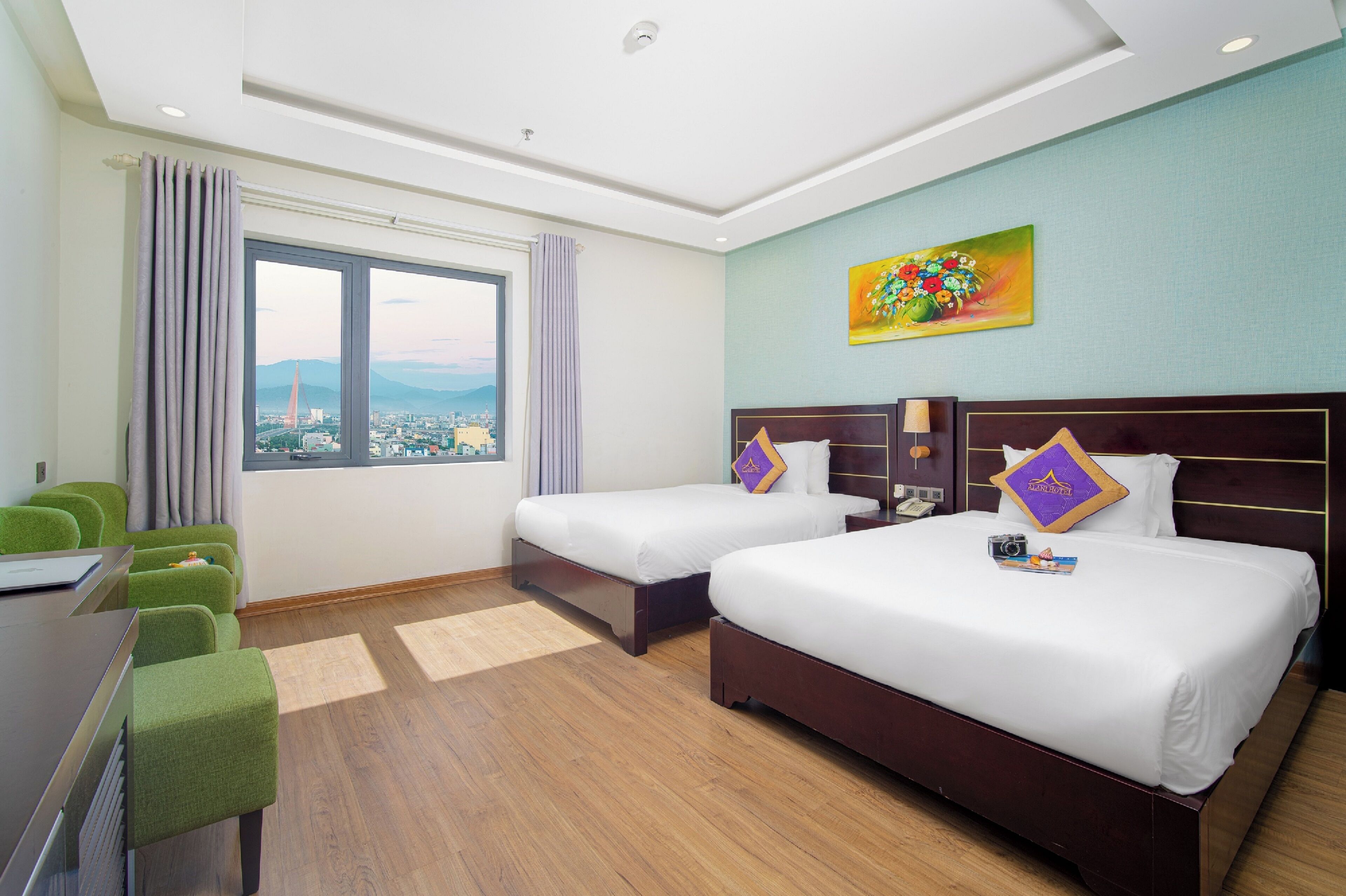 Ein Hotelzimmer mit zwei Betten, einem Schreibtisch und Blick auf die Stadt.
