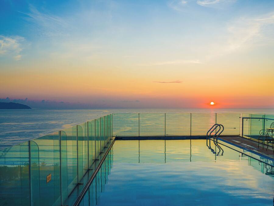 Una piscina al aire libre, sombrillas, sillones reclinables de piscina