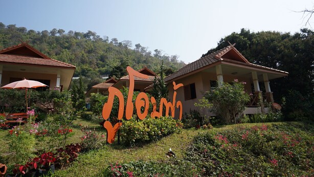 Un complexe hôtelier à l’architecture traditionnelle, une grande enseigne avec des caractères thaïlandais, et de magnifiques jardins luxuriants.