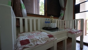 Une chambre avec un lit blanc, une petite table avec un plateau en verre et une fenêtre avec des rideaux.