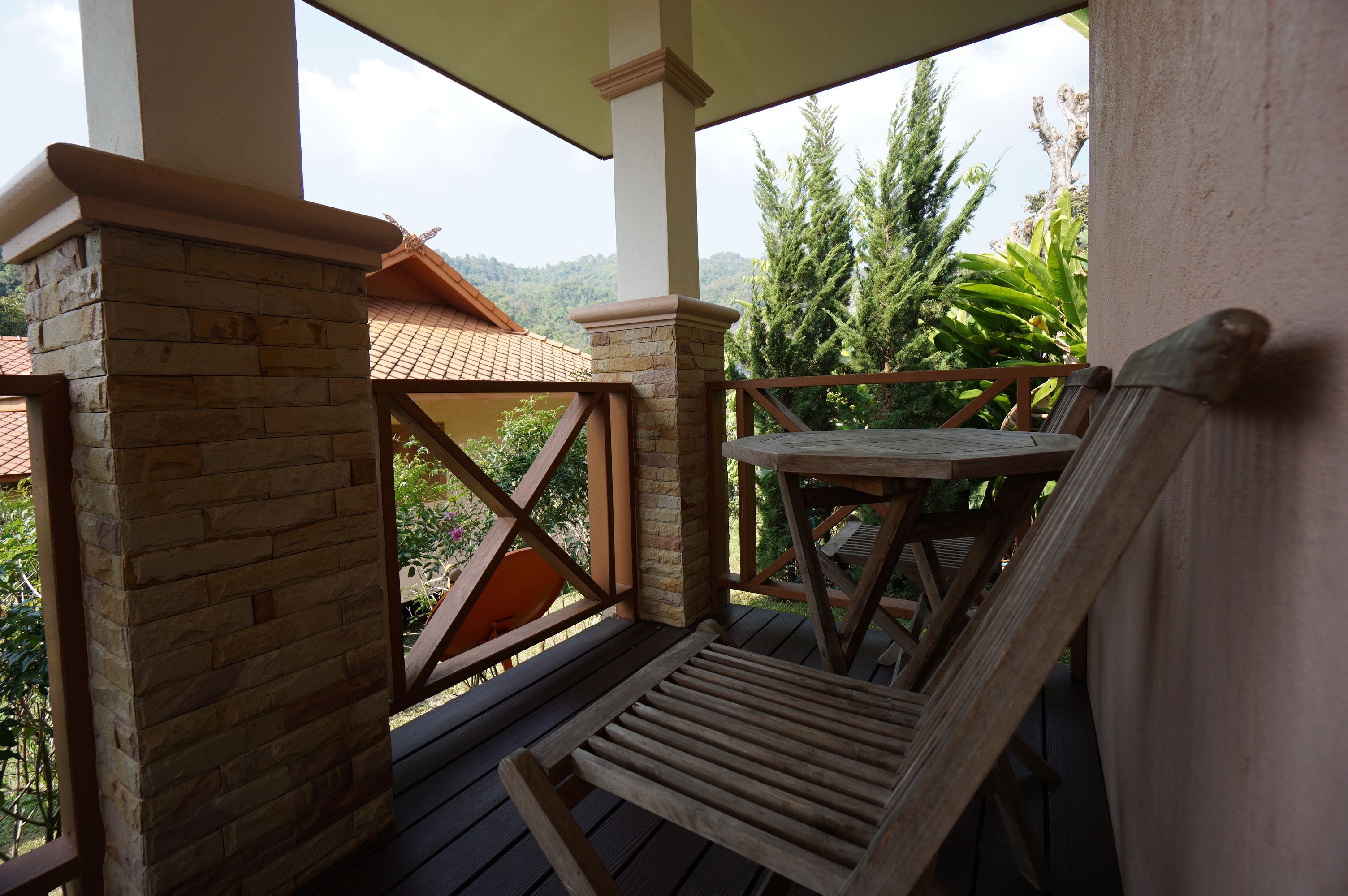 A wooden deck with a brick pillar, a wooden table, and a chair.