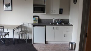 A compact kitchen with a microwave, sink, and white cabinets.