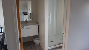 A bathroom with a white sink, mirror, and glass shower enclosure.