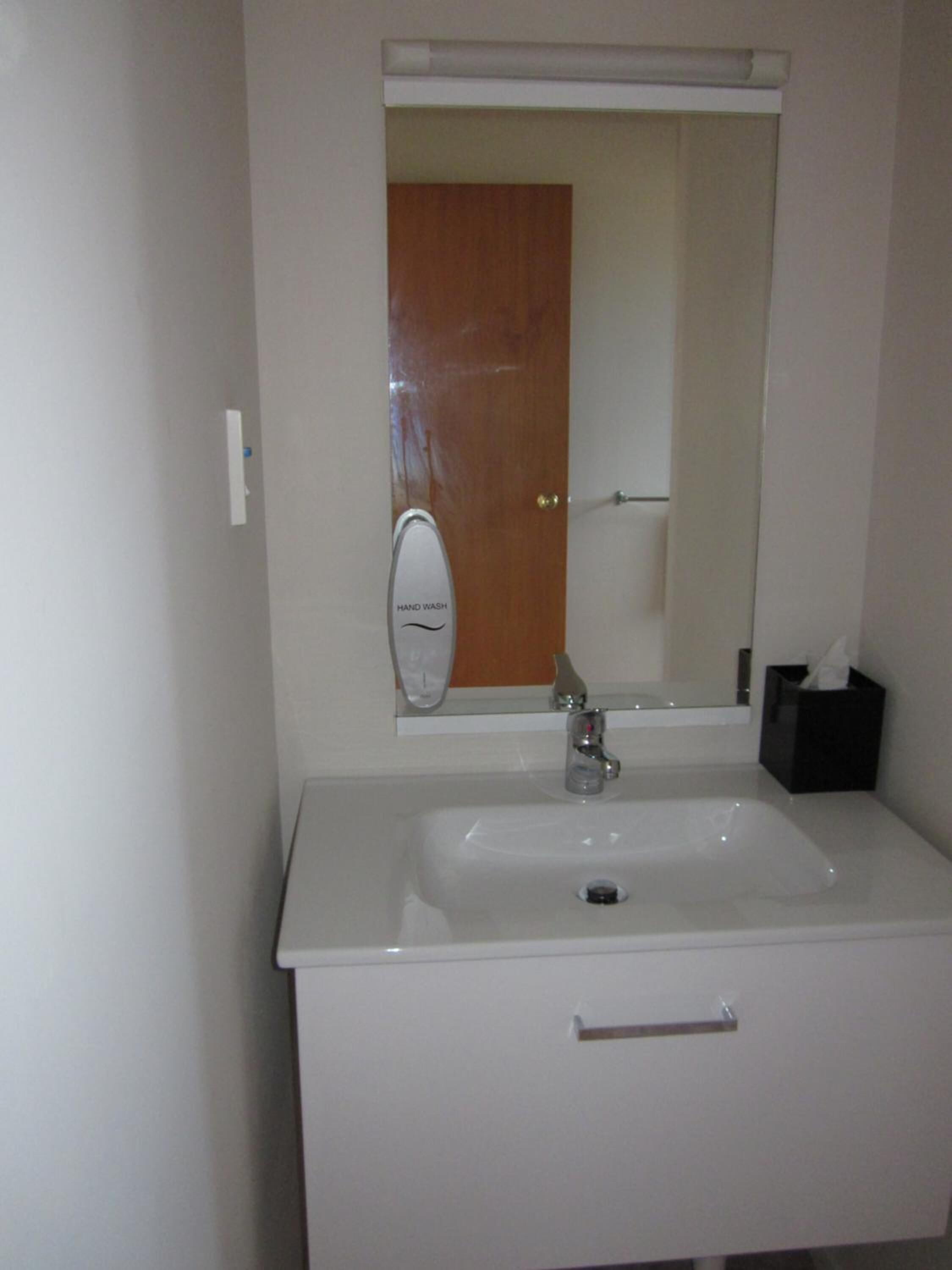 A bathroom with a white sink, a mirror, and a door.