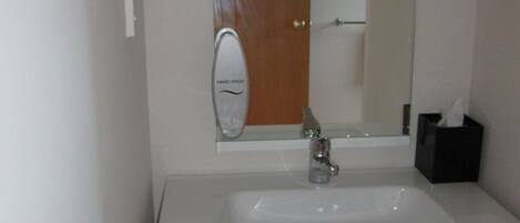 A bathroom with a white sink, a mirror, and a door.