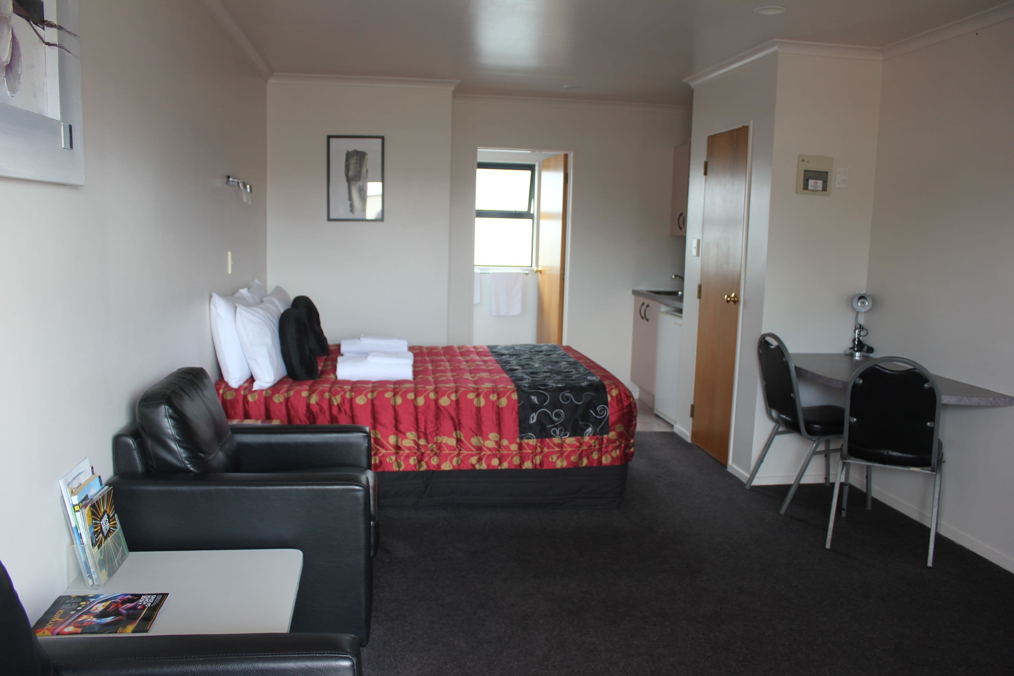 A hotel room with a bed, a desk, a chair, and a small table.