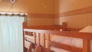 A bunk bed room with a ladder, a ceiling fan, and a window with curtains.