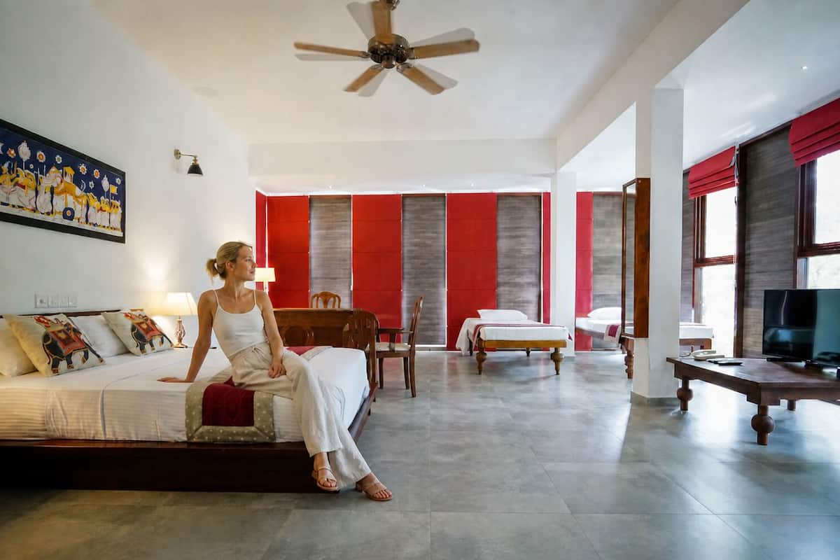 A spacious hotel room with a large bed, a ceiling fan, a TV, and a painting on the wall.