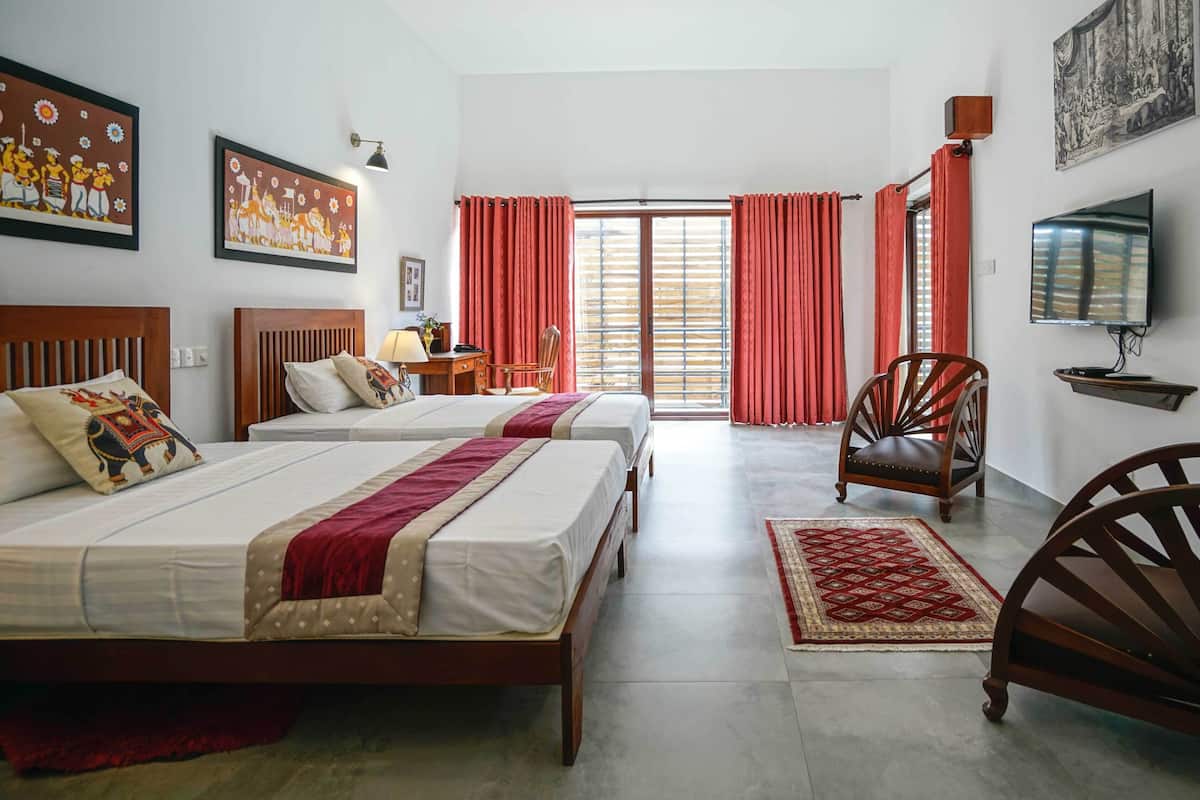 A hotel room with two beds, a TV, a wooden chair, and a red curtain.