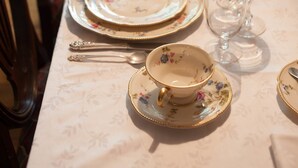 A dining table set with floral-patterned plates, gold-rimmed cups, and clear glassware. - The Denny House (Paint Lick)