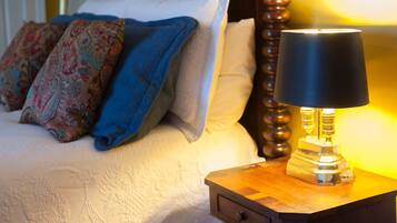 A neatly made bed with patterned pillows, a bedside lamp, and a wooden nightstand.