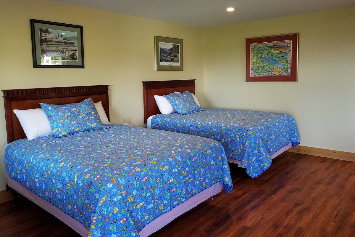 Two beds with matching blue patterned bedspreads, wooden headboards, and white pillows.