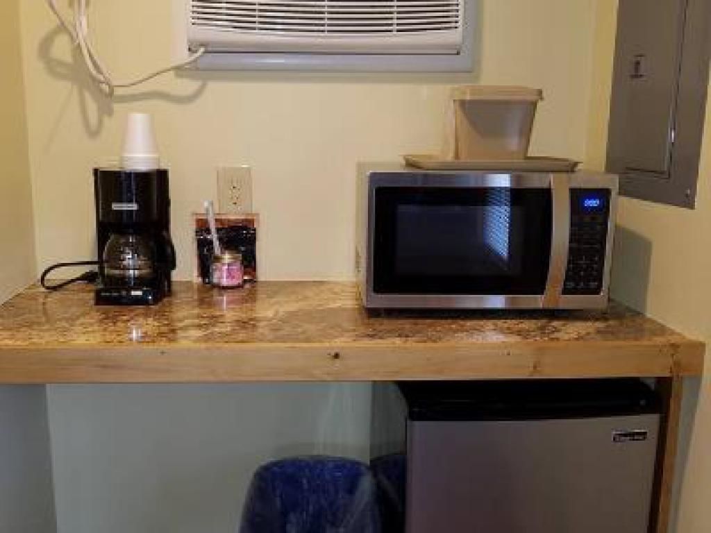 A kitchenette with a microwave, coffee maker, and a small refrigerator.