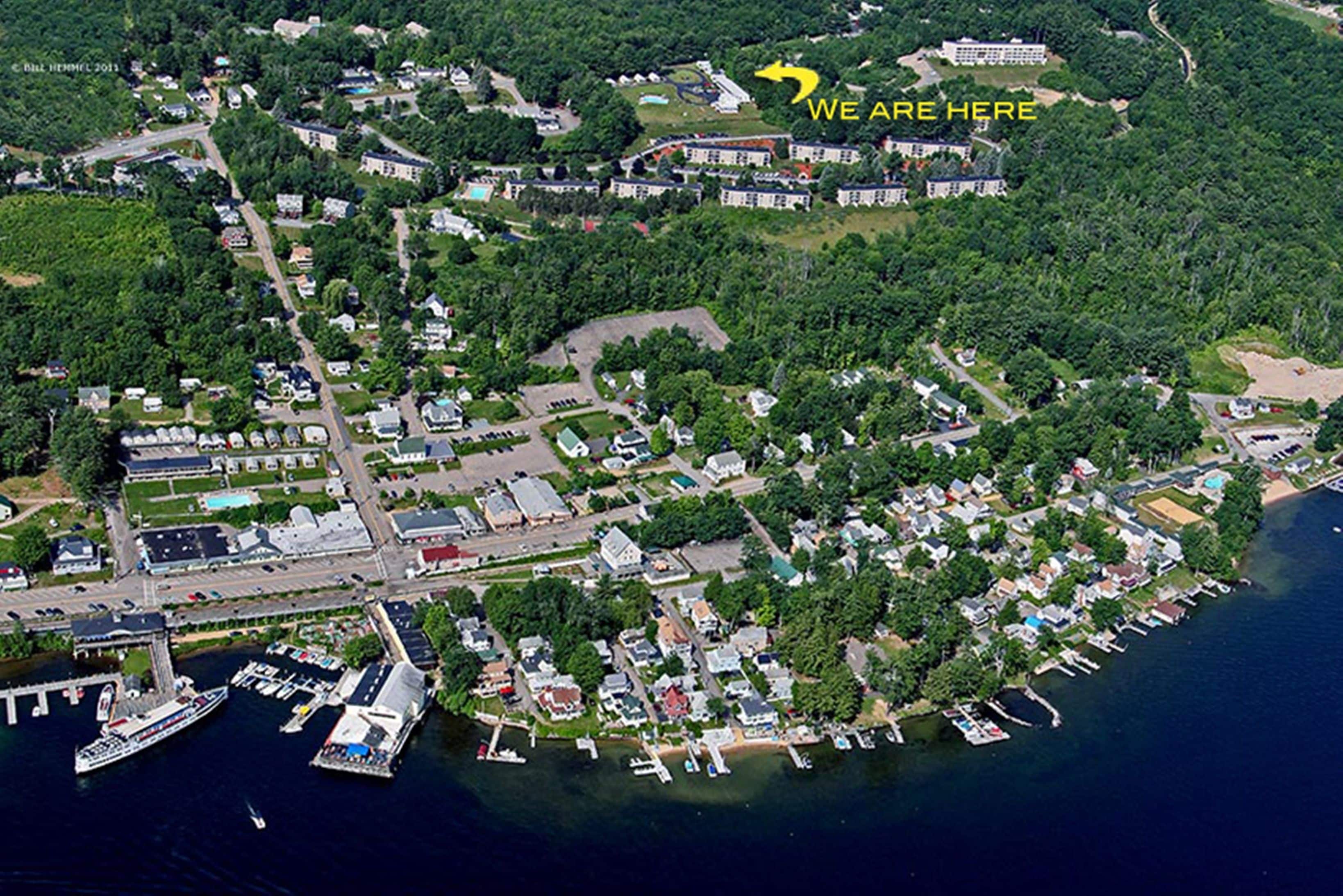 An aerial view of a coastal town with residential areas, a marina, and a large building marked with "WE ARE HERE".
