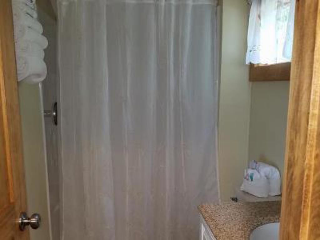 Un baño con cortina de ducha, lavamanos y perchero.