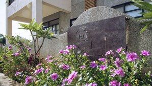 Un edificio con fachada de piedra, un balcón y un letrero con un símbolo de casa.