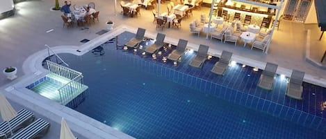 A rooftop pool with lounge chairs and a bar area.