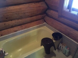 A wooden cabin bathroom with a bathtub, a stool, and toiletries. - Cottage Jokigen (Yamanakako)