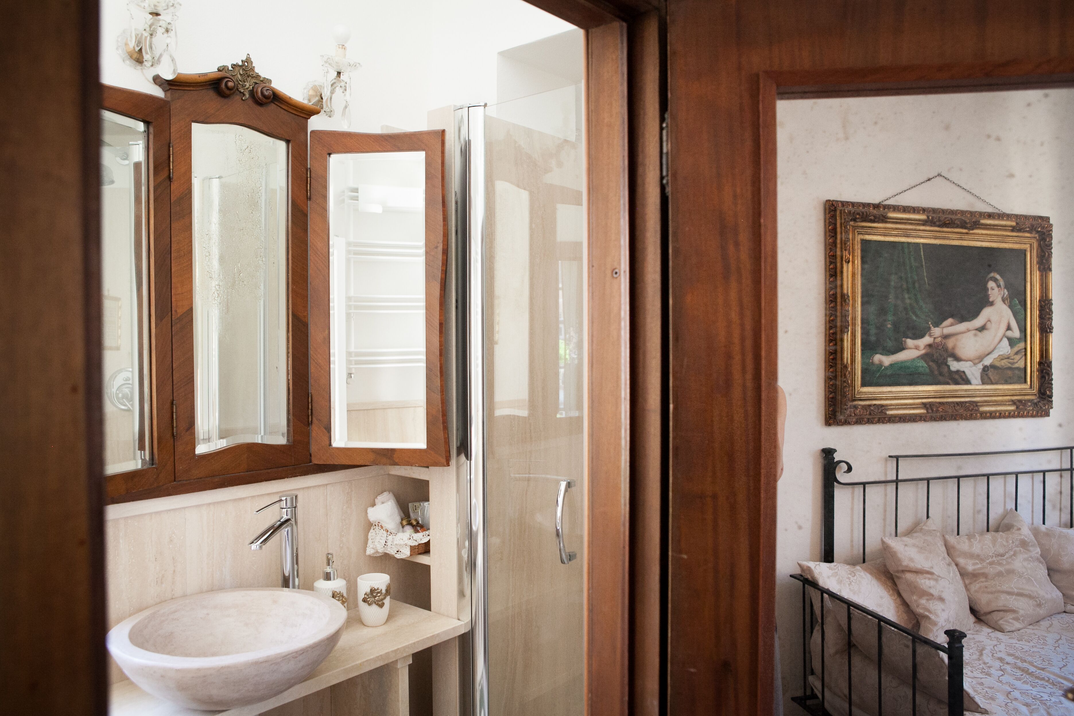 Un bagno con un mobile vanitario in legno, uno specchio grande, un lavandino e un letto con struttura in metallo.