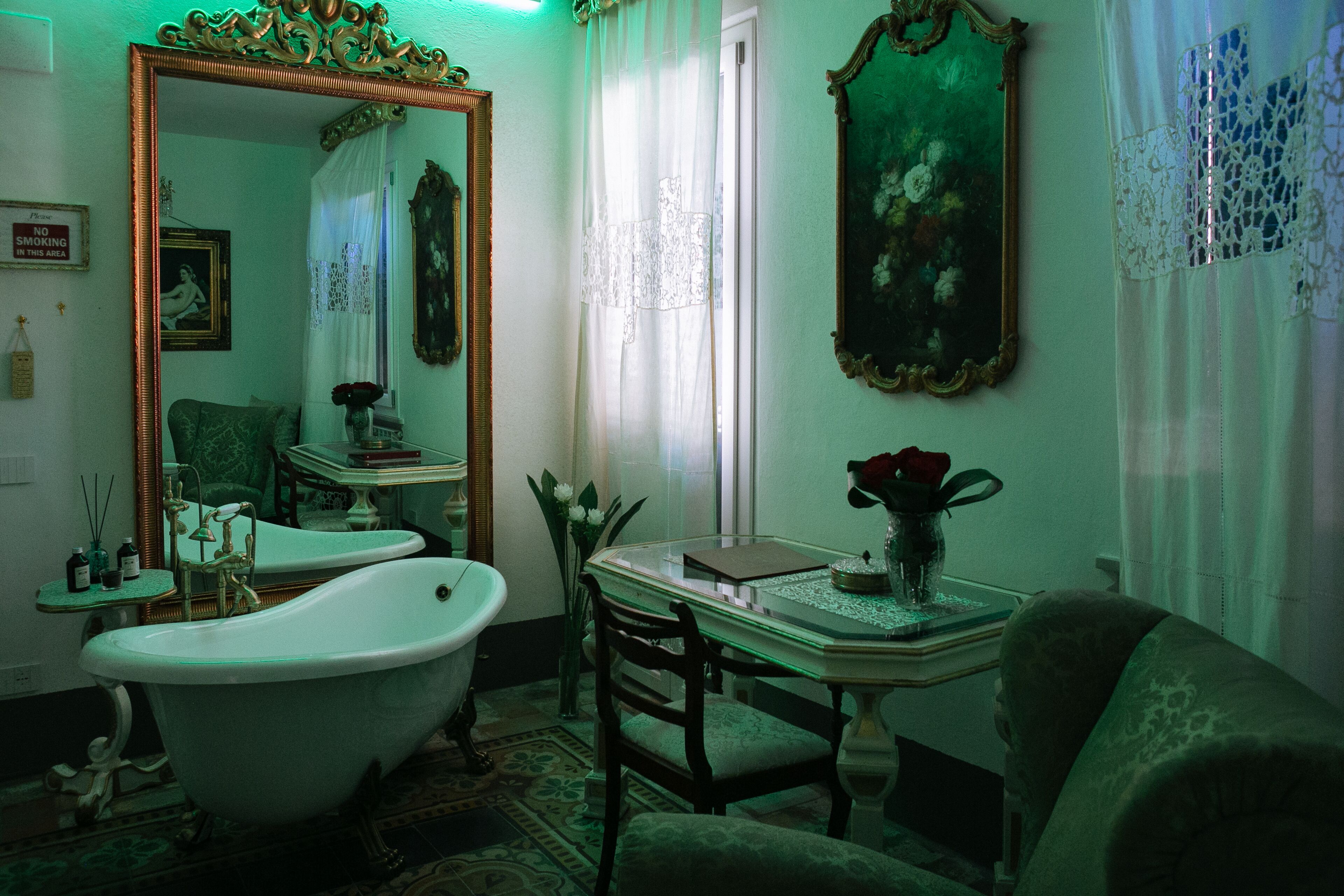 A vintage bathroom with a clawfoot bathtub, a large ornate mirror, and a classic vanity table.