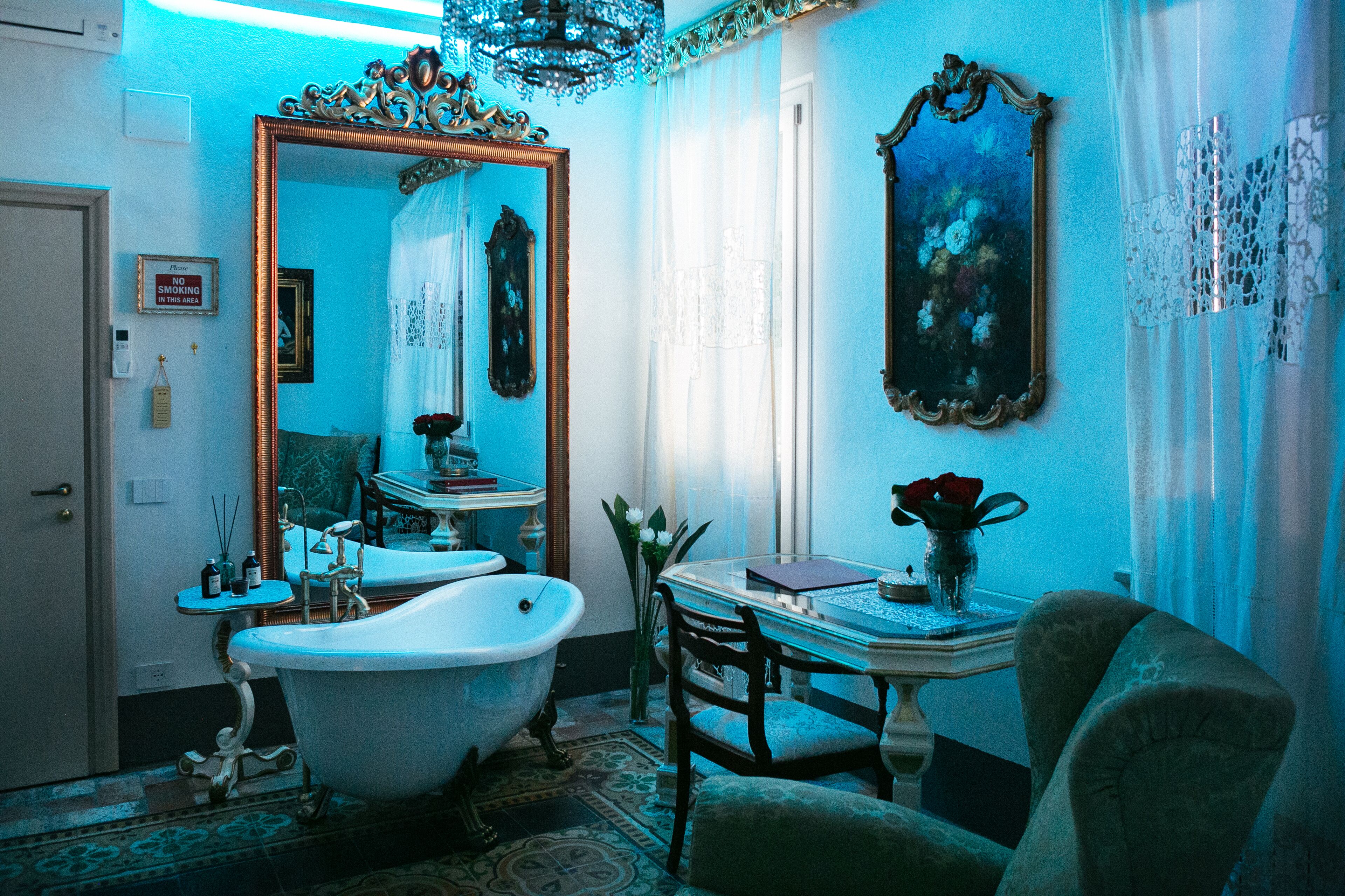 A bathroom with a clawfoot bathtub, a vintage sink, and a mirror with ornate frames.