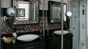Un baño con dos lavamanos, espejos decorativos y una ducha.
