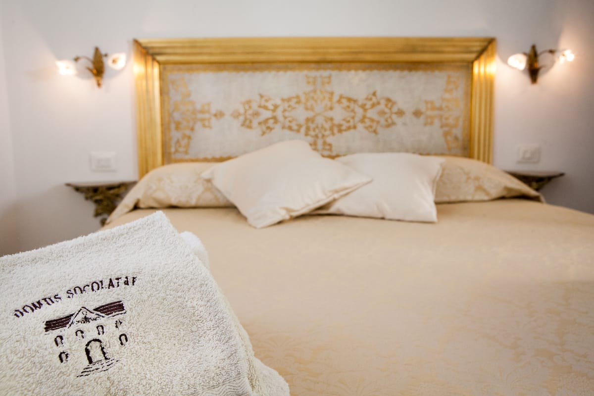 Cama bem arrumada com cabeceira estampada e duas luminárias de mesa.