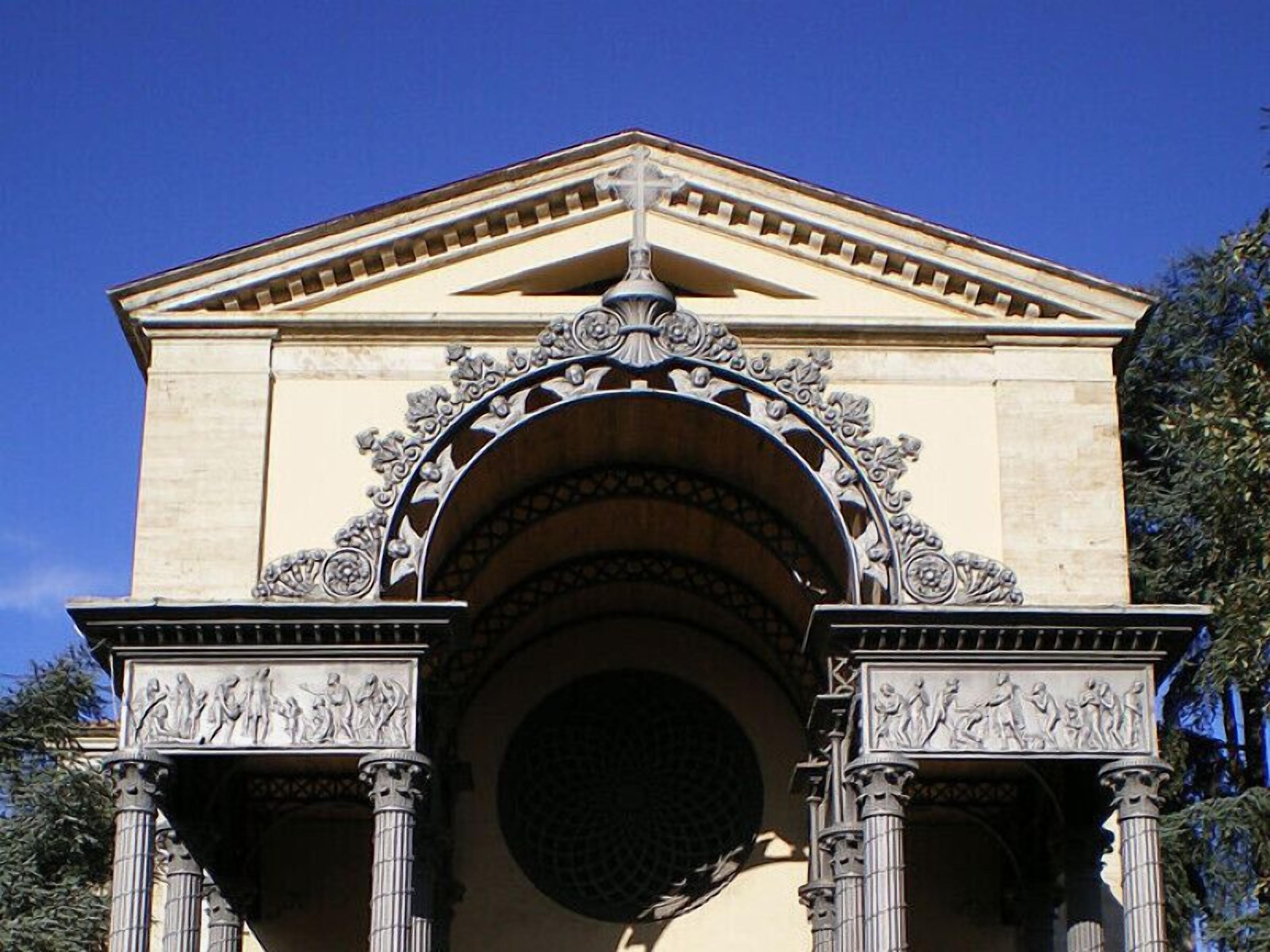 A classical building with an ornate entrance featuring columns and detailed sculptures.