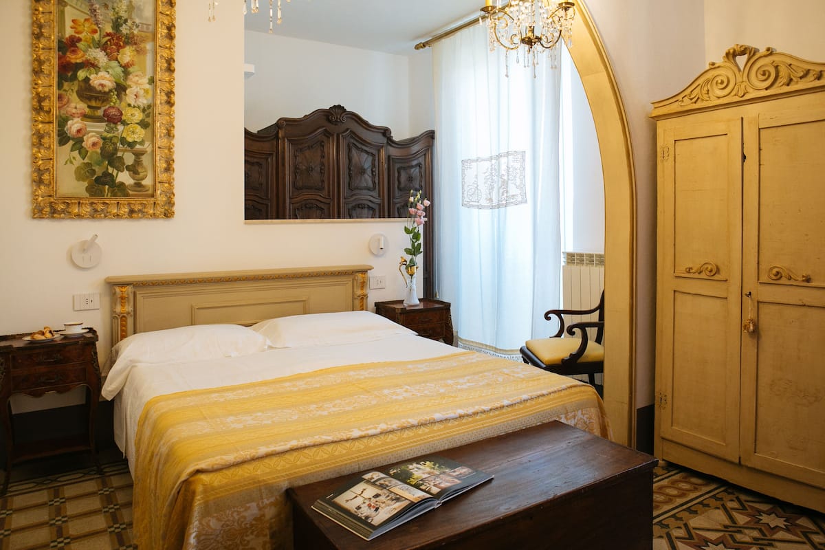 Quarto com cama, mesa de cabeceira, cômoda e espelho.