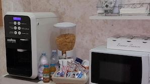 A coffee machine, a microwave, and a basket of food items on a counter. - Napoli Relais (Naples)