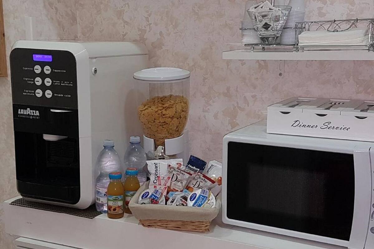 A coffee machine, a microwave, and a basket of food items on a counter.