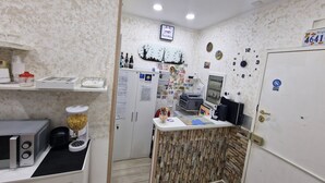 A compact kitchen with a microwave, refrigerator, and a small counter. - Napoli Relais (Naples)